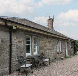 A stone exterior with a table and chairs at Eagle Glen Cottage Kettins near Coupar Angus