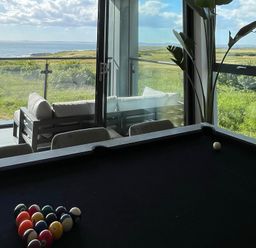 A room with a pool table and a seating area on a balcony with sea views at The Links 40 An apartment with spectacular sea views in Porthcawl