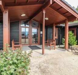 An outdoor entrance with benches and planters at Shore Lodge in Brodick