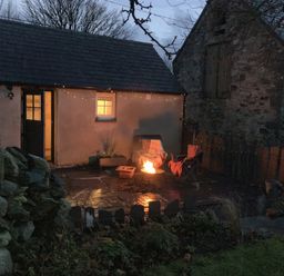An outdoor setting with a fire pit and chairs at Cwt Mochyn in Llanberis