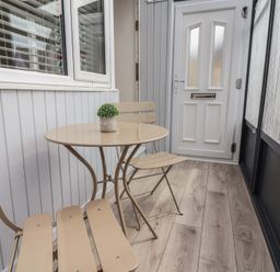A conservatory with a table and chairs at Driftwood in Rhyl