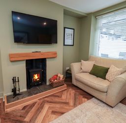 A living room with a television and fireplace at Highfield Cottage in Windermere