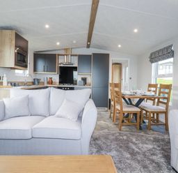 An open plan living area with sofas a dining table with chairs and a kitchen at The Maples No 48 in Hewas Water near Sticker