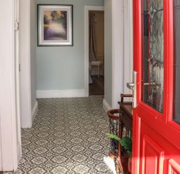 An entrance hallway with patterned floor tiles a red door a small wooden table with plants and a framed picture on the wall at Heatherbell House Ballyhoura near Buttevant