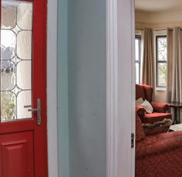 A red front door next to a living room with red armchairs a coffee table and a television at Heatherbell House Ballyhoura near Buttevant