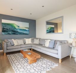 A living room with a gray sectional sofa and wooden coffee table at Coastmans Nest in Mawgan Porth