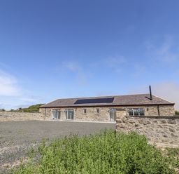 A stone building with solar panels and gravel area at West Burton Hemmel Bamburgh