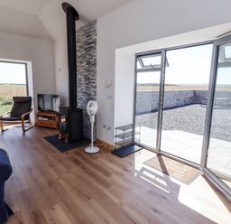 A living room with a sofa and wood stove at West Burton Hemmel in Bamburgh