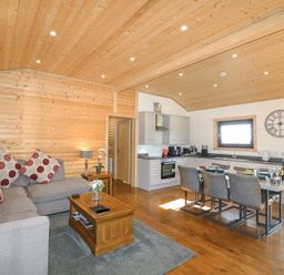 An open living room and kitchen with wooden walls and ceiling at Alpaca Lodge in Barkston