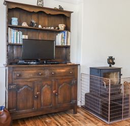 A living room with a wooden cabinet and fireplace at Sea Ledge in Tintagel