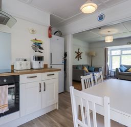A kitchen with appliances and a dining table at Sea Ledge in Tintagel