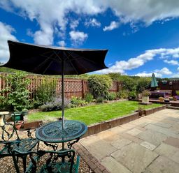 A garden with a table and chairs under an umbrella at Harefield in Rothbury
