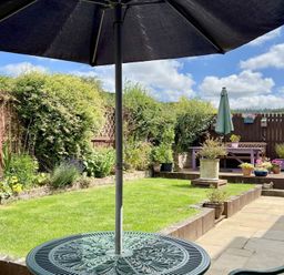 A garden with a table, umbrella, and seating area at Harefield in Rothbury
