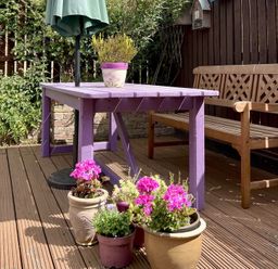 A garden with a purple table, wooden bench, and flower pots at Harefield in Rothbury