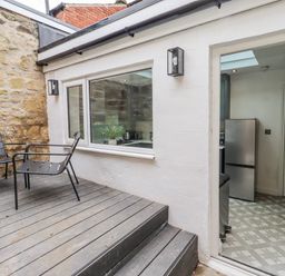 An outdoor seating area with chairs and a door leading to a kitchen at 3 Lisburn Street Alnwick