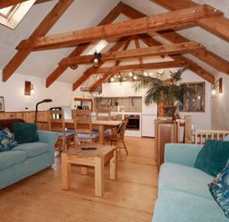 A living room with a sofa and dining table at Stribleys Barn in Cusgarne near St Day