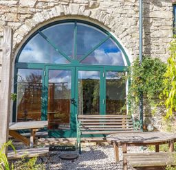 A garden area with arched doors and outdoor seating at Stribleys Barn, Cusgarne, Truro