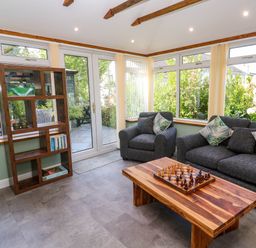 A living room with gray sofas and a wooden coffee table with a chess set at Little Acorns in Gweek