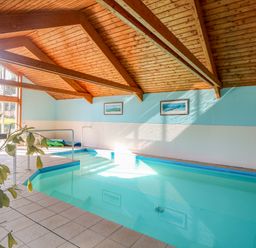 An indoor swimming pool with handrails and framed pictures on the wall at Swallow Barn in Holton near Halesworth