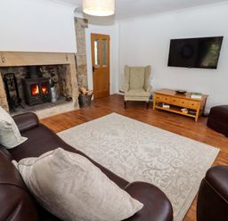 A living room with a fireplace and sofa at The Lodge in Powburn