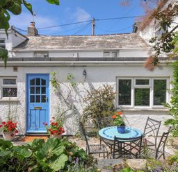 A garden with a blue door and a table with chairs at 2 Porthilly Cottages Rock
