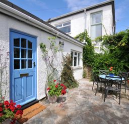 A garden with a blue door and a table with chairs at 2 Porthilly Cottages Rock