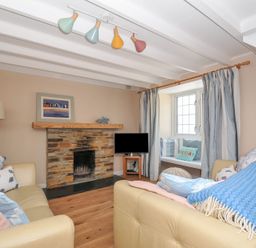A living room with a fireplace and sofa at 2 Porthilly Cottages in Rock