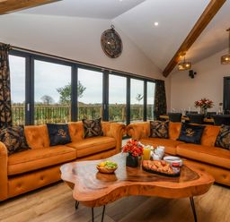 A living room with two orange sofas around a wooden coffee table and a dining table in the background at Routhorpe Lodge in Bainton near Great Driffield