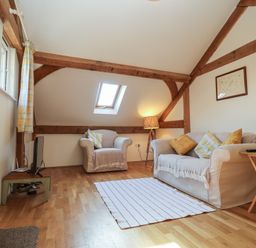 A living room with sofas pillows and a lamp at Woodland Retreat Lodge Brundish near Laxfield