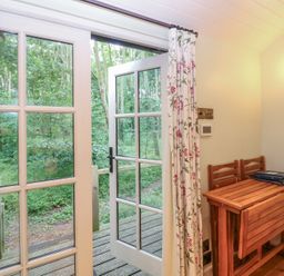 A room with a table and chairs leading to an outdoor area at Woodlands Retreat Shepherd's Hut Brundish near Laxfield