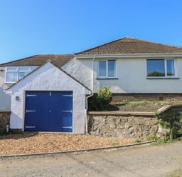 A detached house with a tiled roof and blue garage doors at Arfryn in Solva