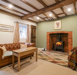 A living room with a leather sofa wooden coffee table fireplace and exposed wooden beams at 2 Loxter Villas in Wellington Heath near Ledbury