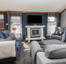 A living room with two sofas an armchair a fireplace and a television at Sunset Retreat South Lakeland Leisure Village near Carnforth