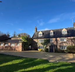 A stone house with multiple windows and ivy on the walls under a blue sky at Dragon House in Bilbrook near Minehead