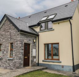A stone and plaster exterior house with a dark wooden door and windows at C65 Cahermore Holiday Village in Enniscrone County Sligo