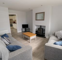 A living room with two grey sofas a wooden coffee table a small TV and a wood stove at C65 Cahermore Holiday Village in Enniscrone County Sligo