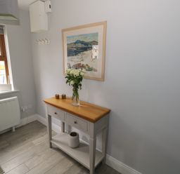 A hallway with a console table holding flowers and decorations and a window with a garden view at C65 Cahermore Holiday Village in Enniscrone County Sligo