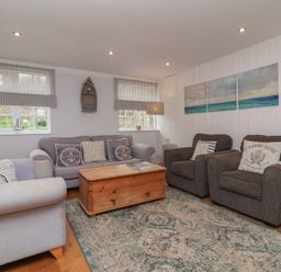 A living room with sofas armchairs a wooden coffee table and paintings at Gatekeeper's Cottage Bilbrook near Minehead