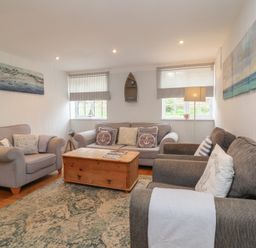 A living room with sofas a wooden coffee table a patterned rug and wall art at Gatekeeper's Cottage in Bilbrook near Minehead