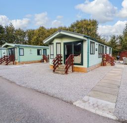 A group of green mobile homes with small stairs and outdoor seating areas at Lodge 4 in Silverdale
