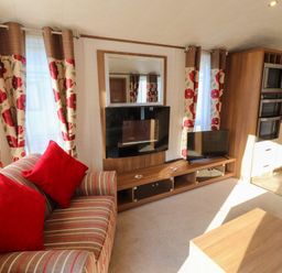 A living room with striped sofa and red pillows a television and floral curtains at Lodge 4 in Silverdale