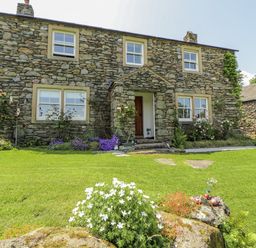 A stone house with garden and flowers at High Wood Foot in Bampton, Cumbria