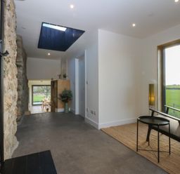 An entrance hall with a stone wall and a skylight at Tithe Barn Lodge Capel Mawr near Malltraeth