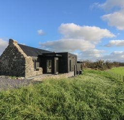 A building with a field and fence at Tithe Barn Lodge Capel Mawr near Malltraeth