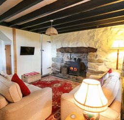 A sitting room with two sofas a lit fireplace and a wall mounted television at Tyn Y Graig in Fairbourne