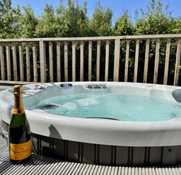 A hot tub with a champagne bottle and glass at The Black Barnacle in Portreath