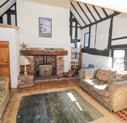 A living room with two sofas a fireplace and a bookshelf at Wyre Court Cottage in Bewdley