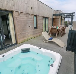 An outdoor area with a hot tub and dining set at Dahlia in Portreath