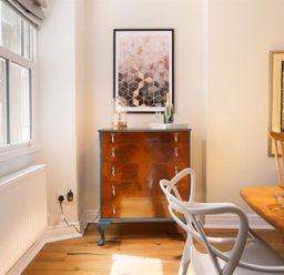 A dining area with wooden floor a chest of drawers and modern chairs at Bellflower Cottage in Windermere