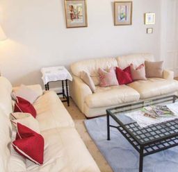A sitting room with two cream sofas with pillows and a glass coffee table at Bank View in Chirnside